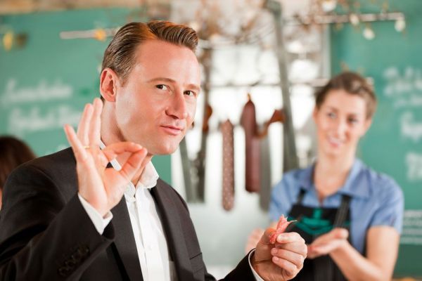 Zufriedener Kunde an der Theke macht das OK-Zeichen mit der Hand