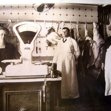 Foto aus dem frühen 20ten Jahrhundert - Menschen stehen neben einer Waage und Wiegen Fleischprodukte ab